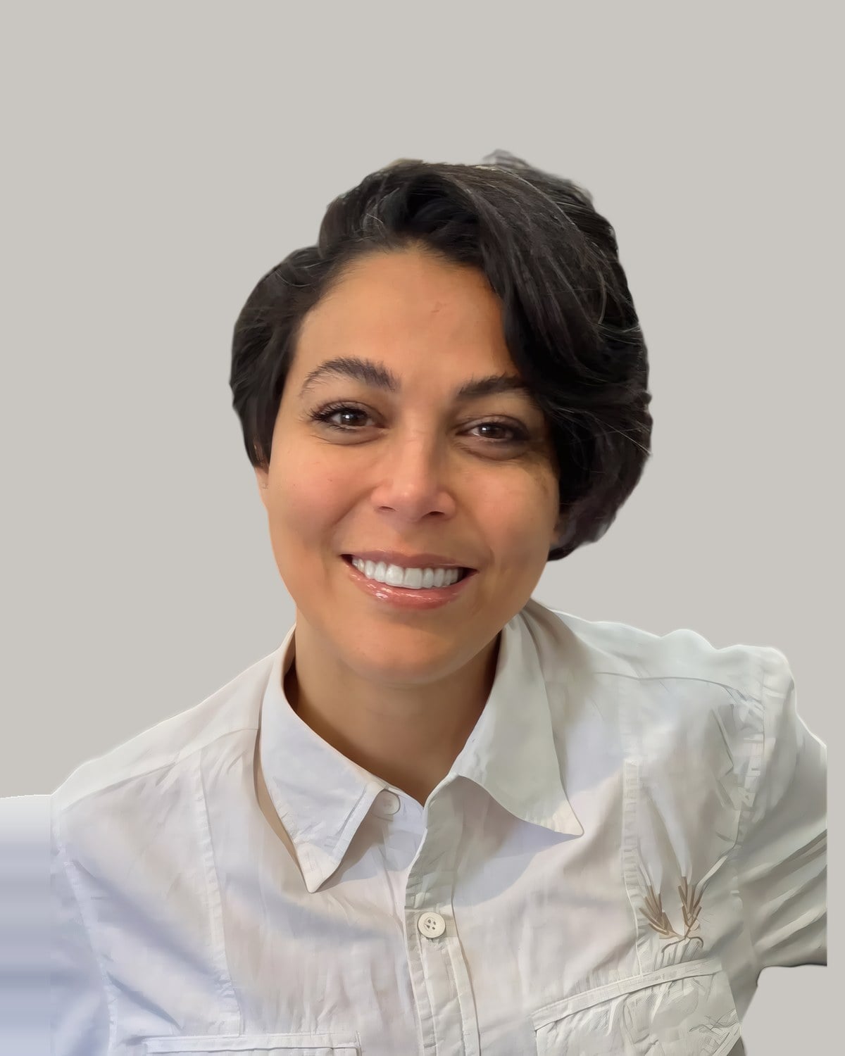 Smiling woman in a white shirt with a short dark pixie swept to one side