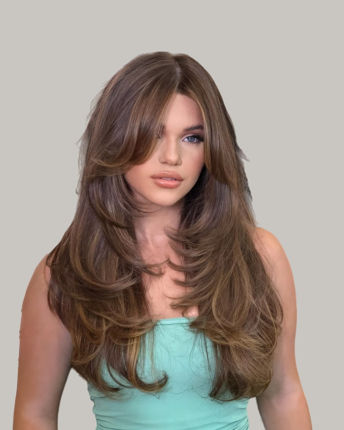 Woman in a teal top with long brown hair and curtain-style face-framing layers