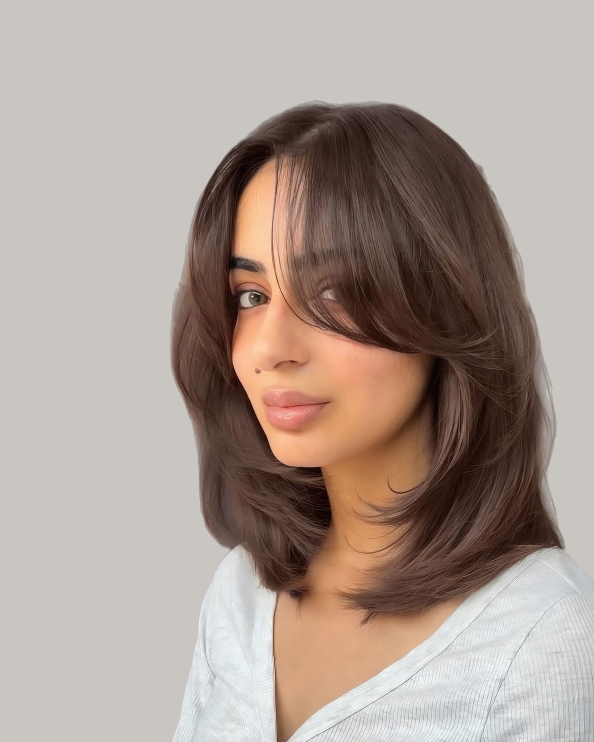 Woman with collarbone-length brown hair and long bangs, seen from a three-quarter angle