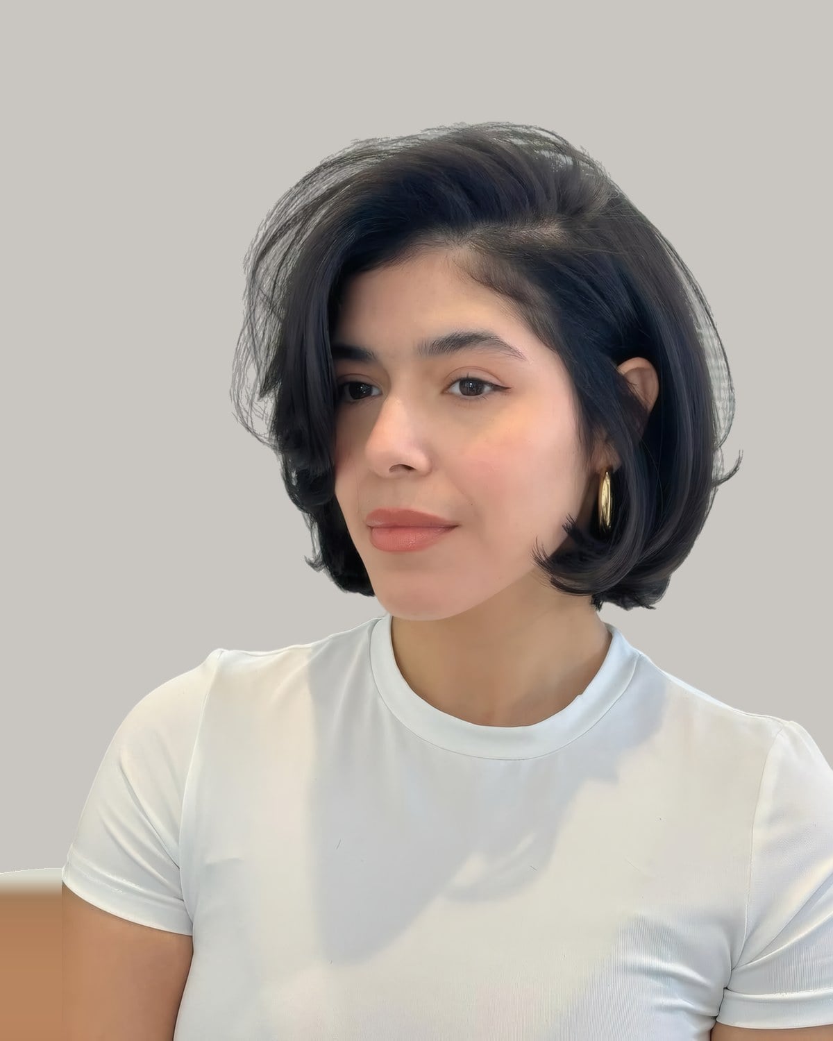 Woman in a white T-shirt with a jaw-length black bob and a deep side part