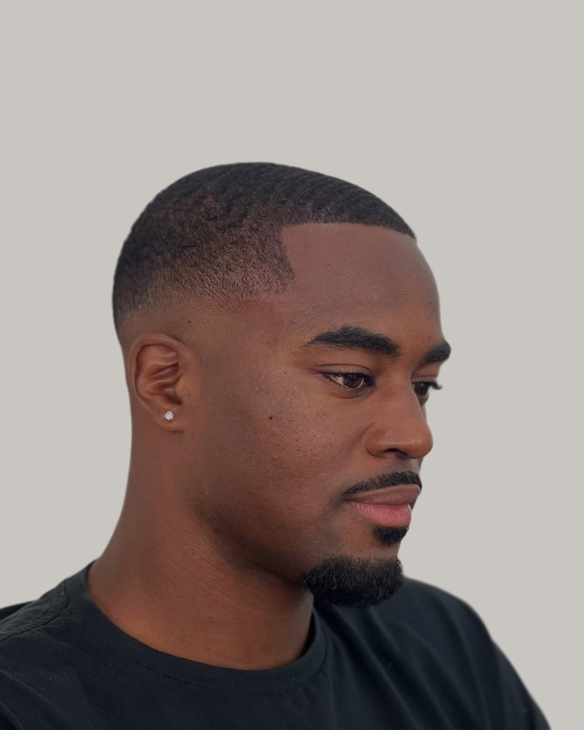 Black man with a buzz cut and a low fade, seen in profile
