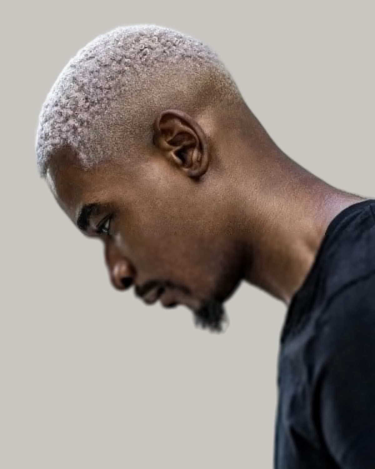 Black man with a silver-blond bleached buzz cut, seen in profile