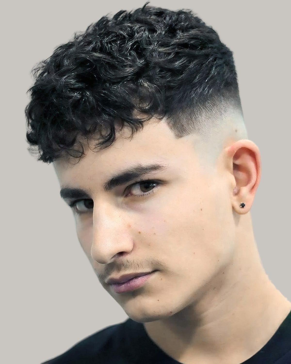 Man with curly hair on top and a high skin fade, seen in profile