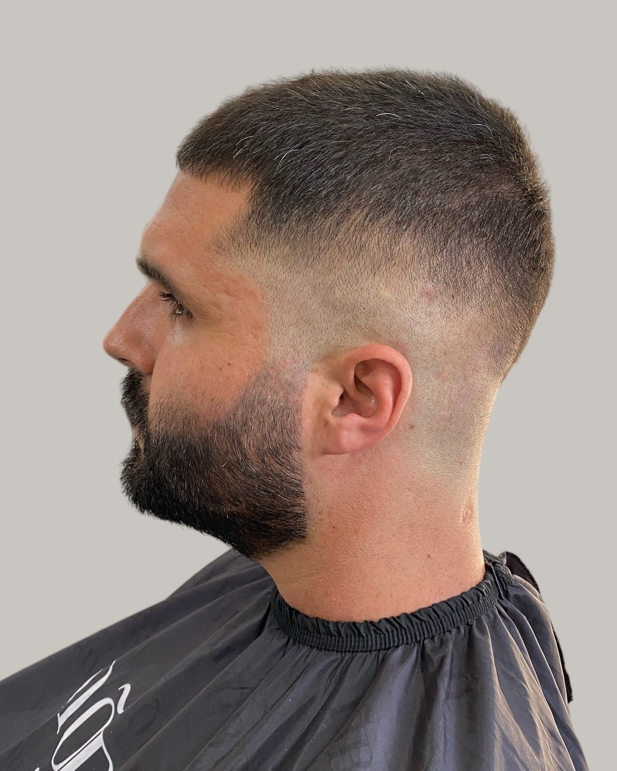 Man with a buzz cut and a faded beard, seen in profile