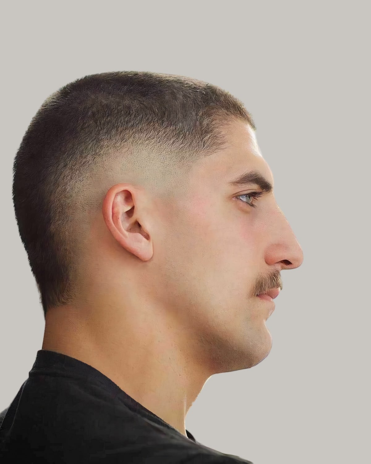 Man with a grown-out buzz cut, a burst fade and a mustache, seen in profile