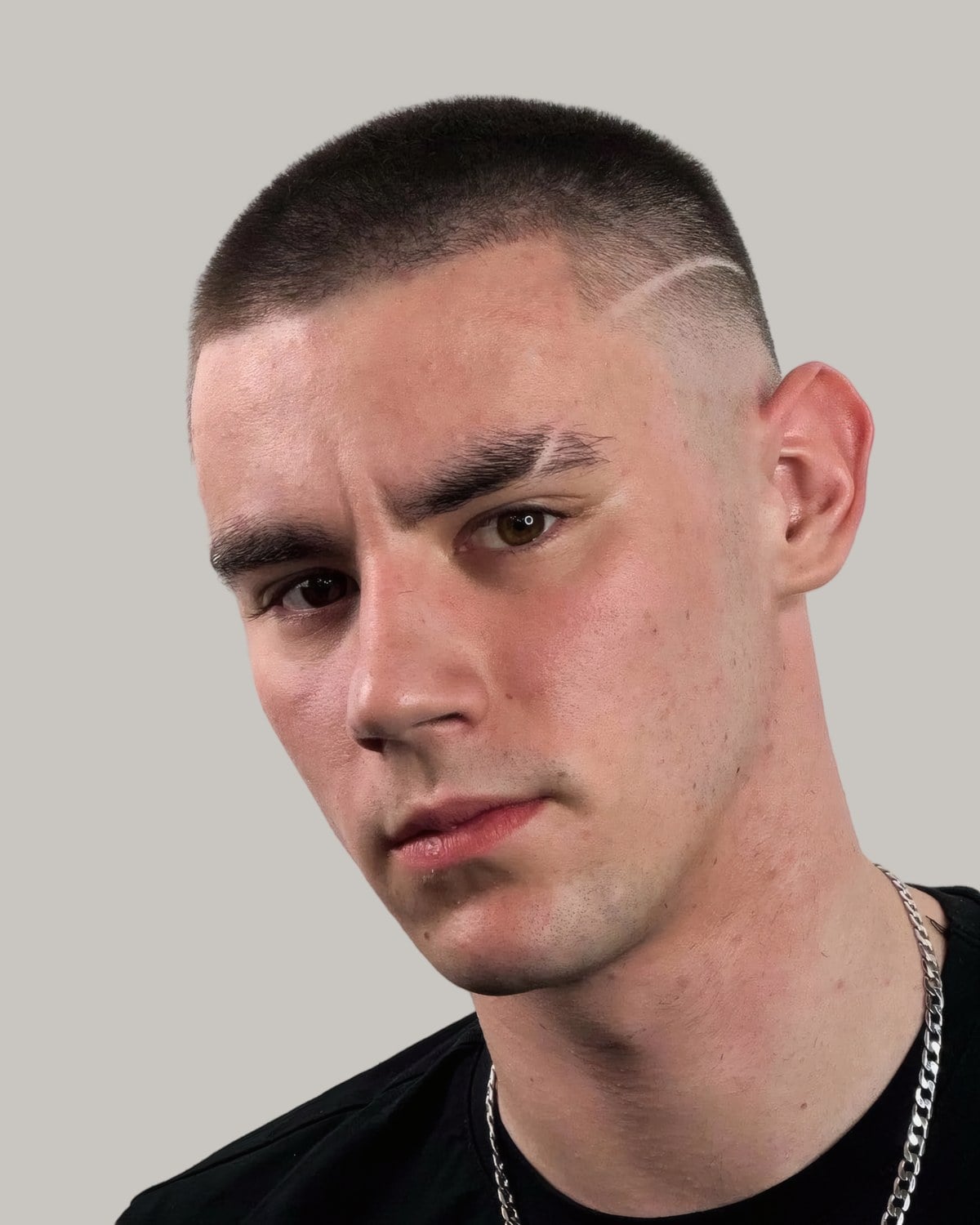 Man with a buzz cut, a hard part and a skin fade, facing the camera