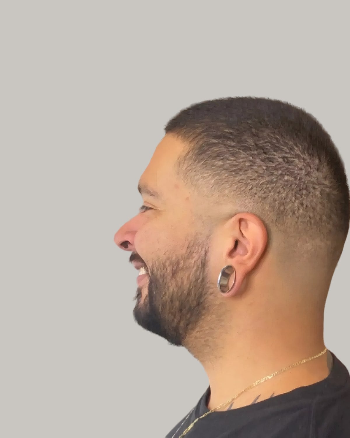 Man with a buzz cut and a low taper, seen in profile