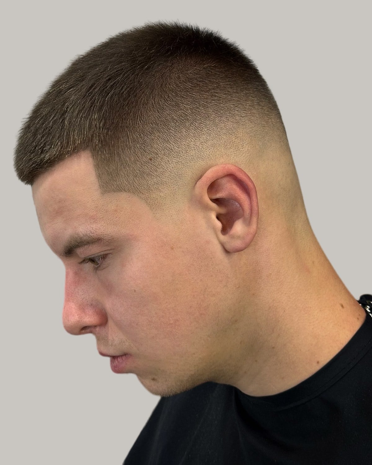 Man with a buzz cut and a mid skin fade, seen in profile