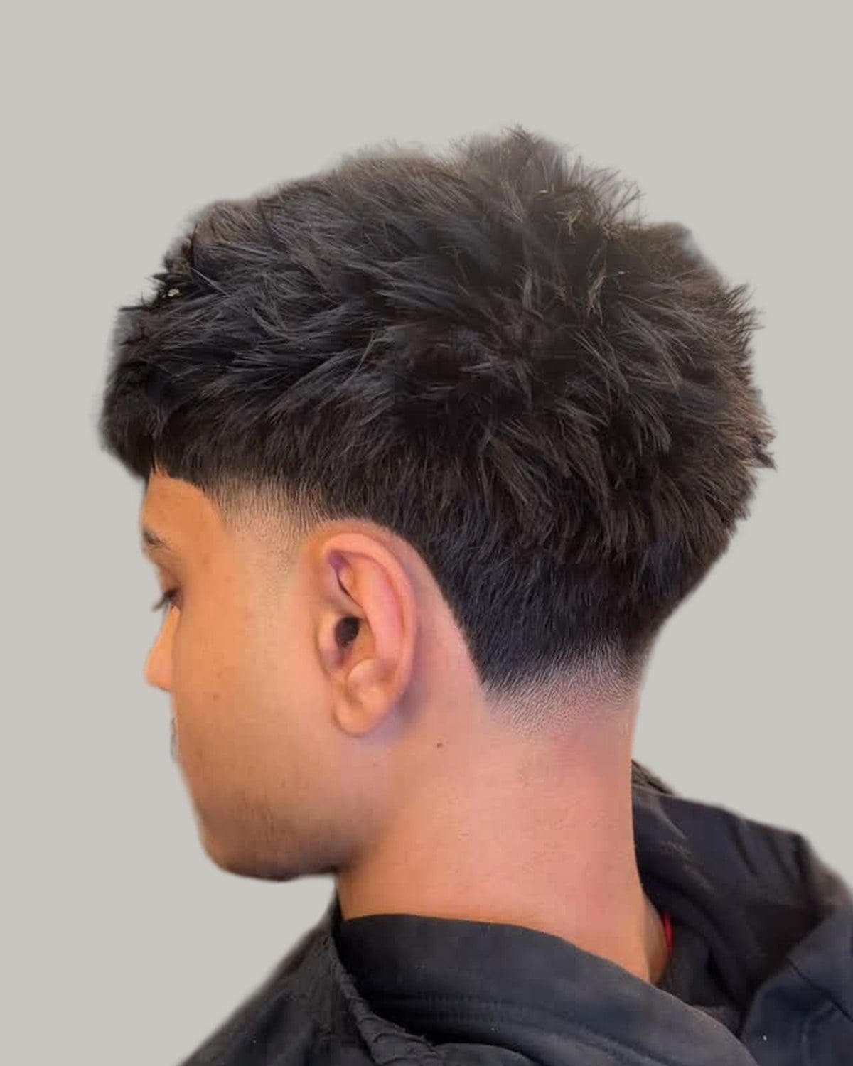 Young man with a number 12 buzz cut and a mid taper, seen from behind at an angle