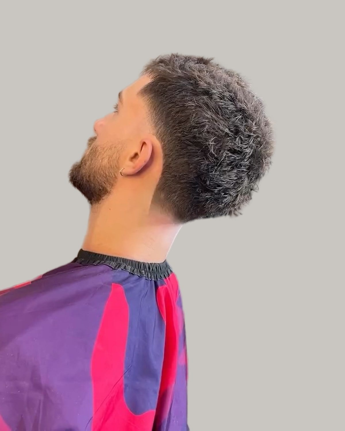 Bearded man with a number 8 buzz cut and a high taper, in profile with his head tilted back