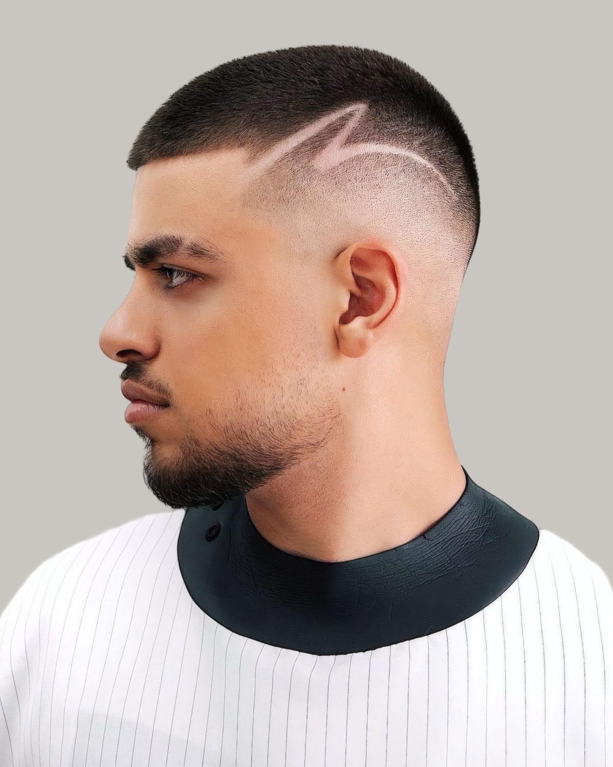 Black man with a buzz cut and a shaved design above the ear, seen in profile