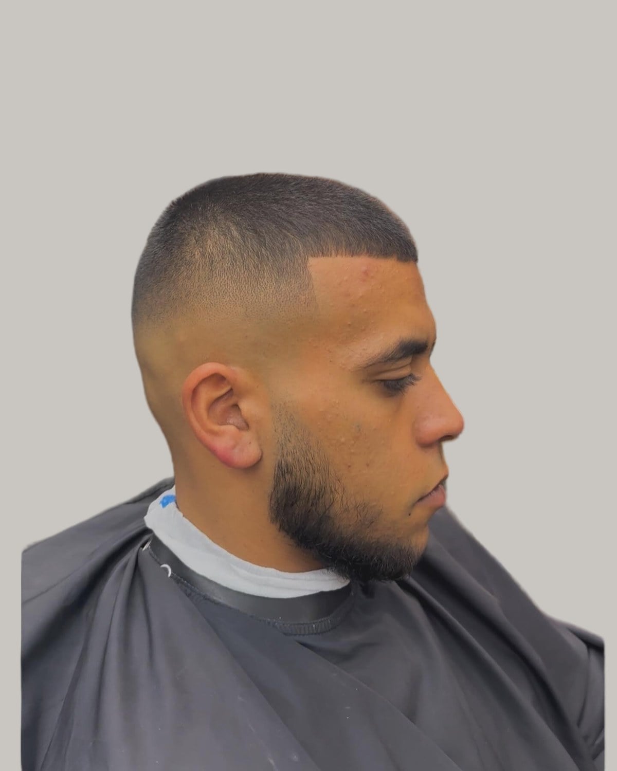 Man with a buzz cut on thick dark hair and a skin fade, seen in profile