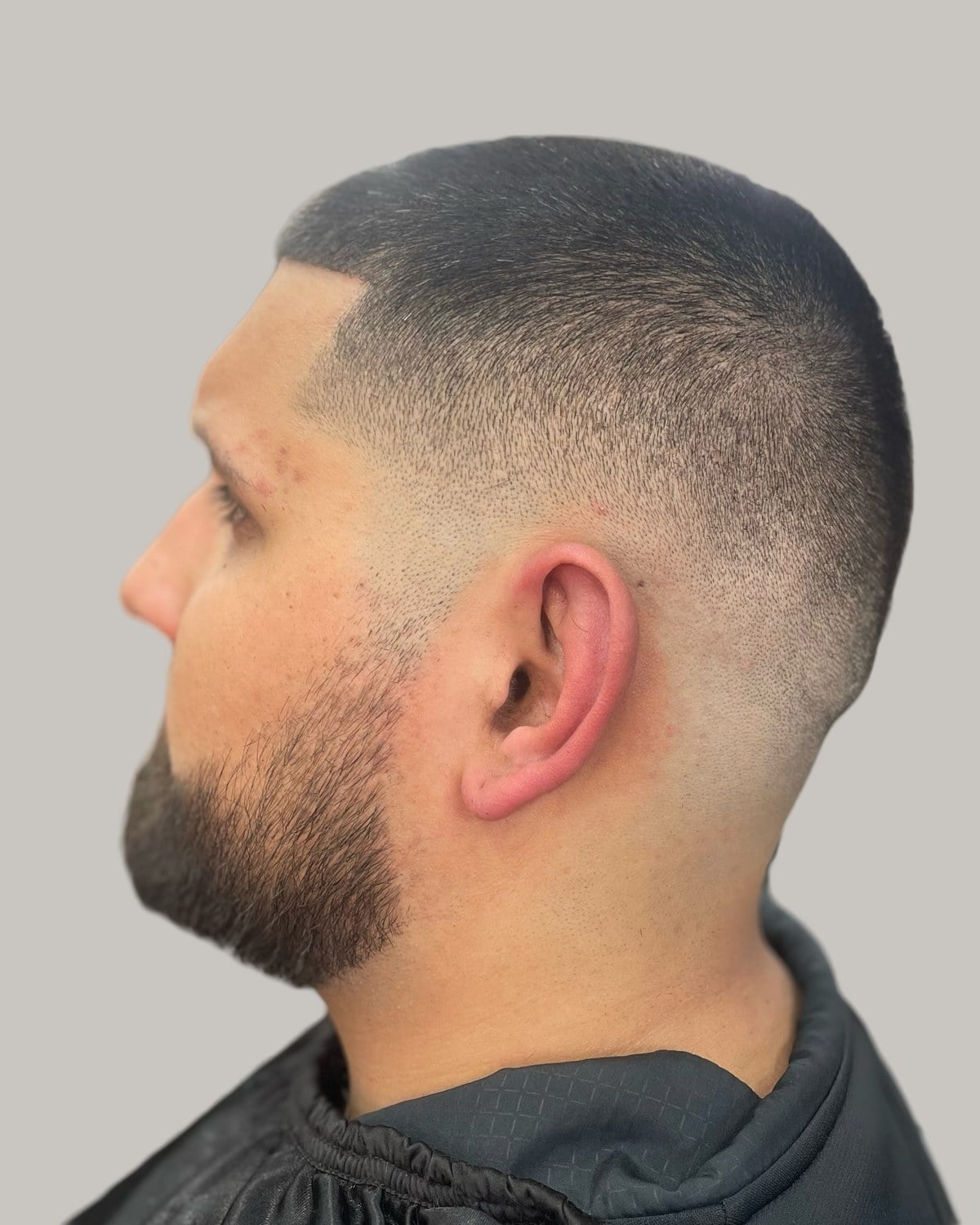 Man with a buzz cut and a full dark beard, seen in profile