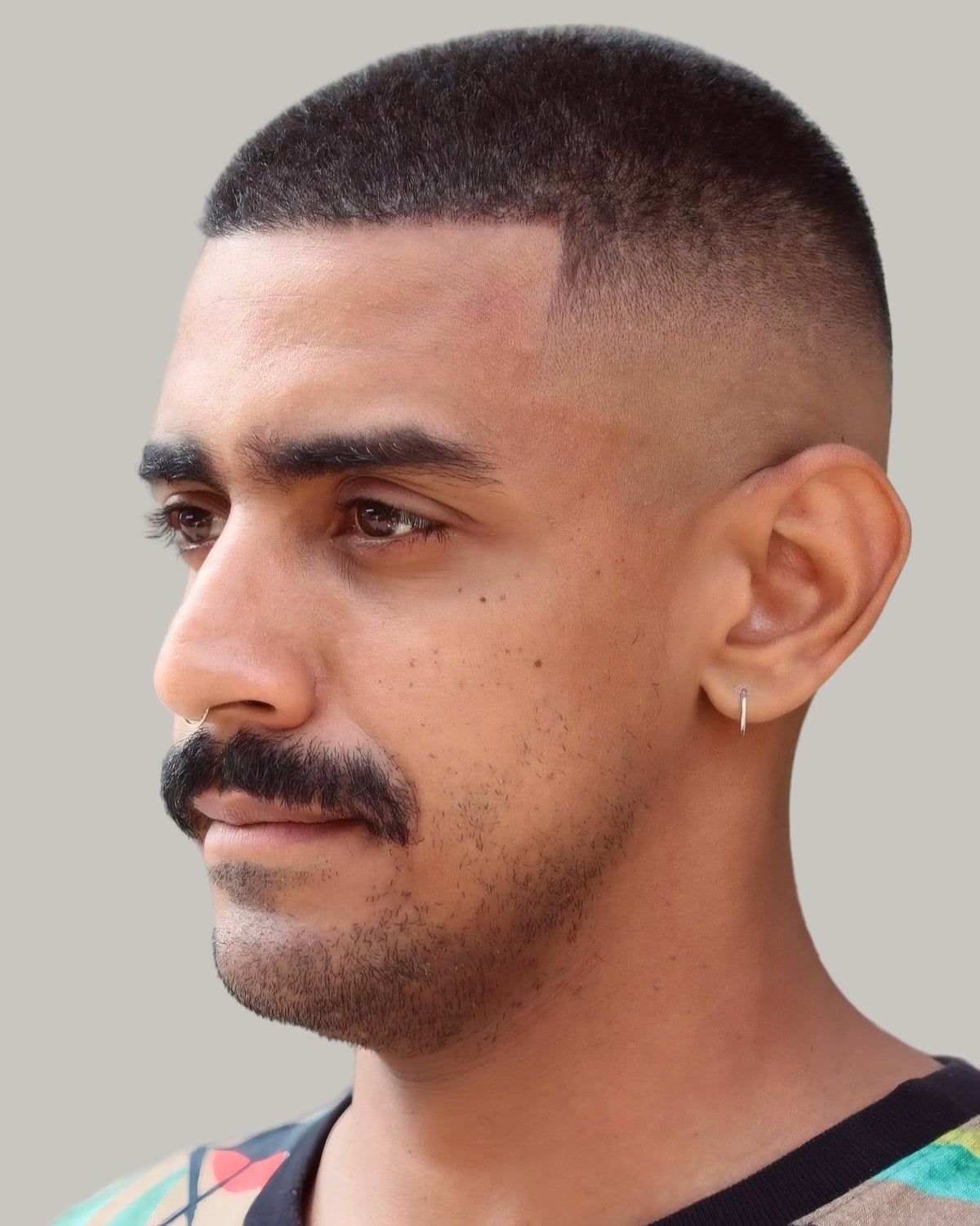 Man with a buzz cut, a mid fade and a full mustache, seen in profile