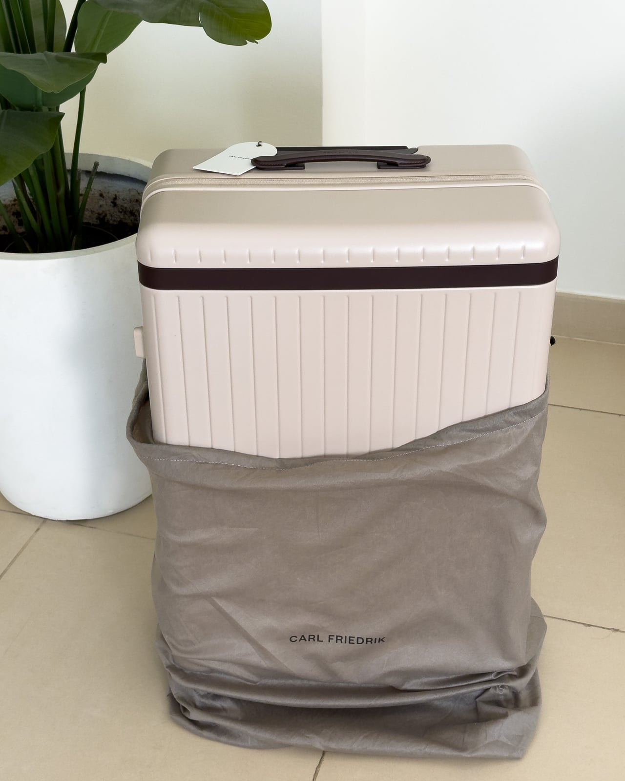 Carl Friedrik suitcase half out of its grey branded dust bag - Luxe Digital