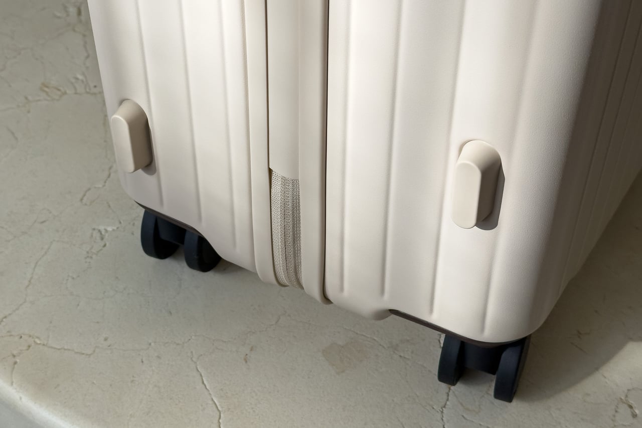 Lower corner of the Sand/Chocolate Carl Friedrik suitcase with its feet and spinner wheels - Luxe Digital