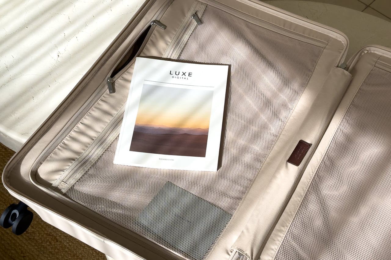 A Luxe Digital magazine inside one half of the open Carl Friedrik suitcase - Luxe Digital