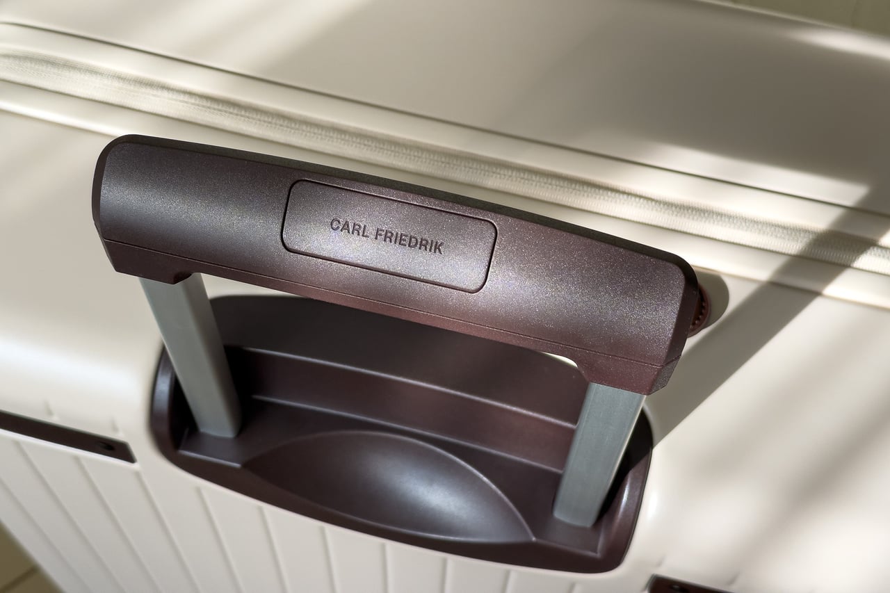 Carl Friedrik branded telescopic trolley handle raised from its recess - Luxe Digital