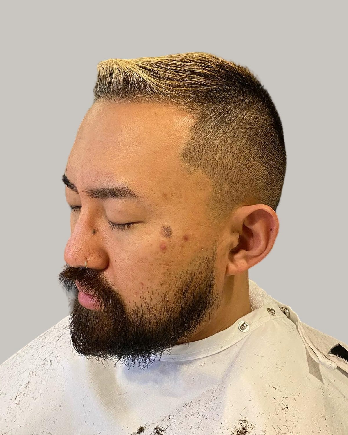 Bearded man with a short crew cut on straight hair, seen at an angle