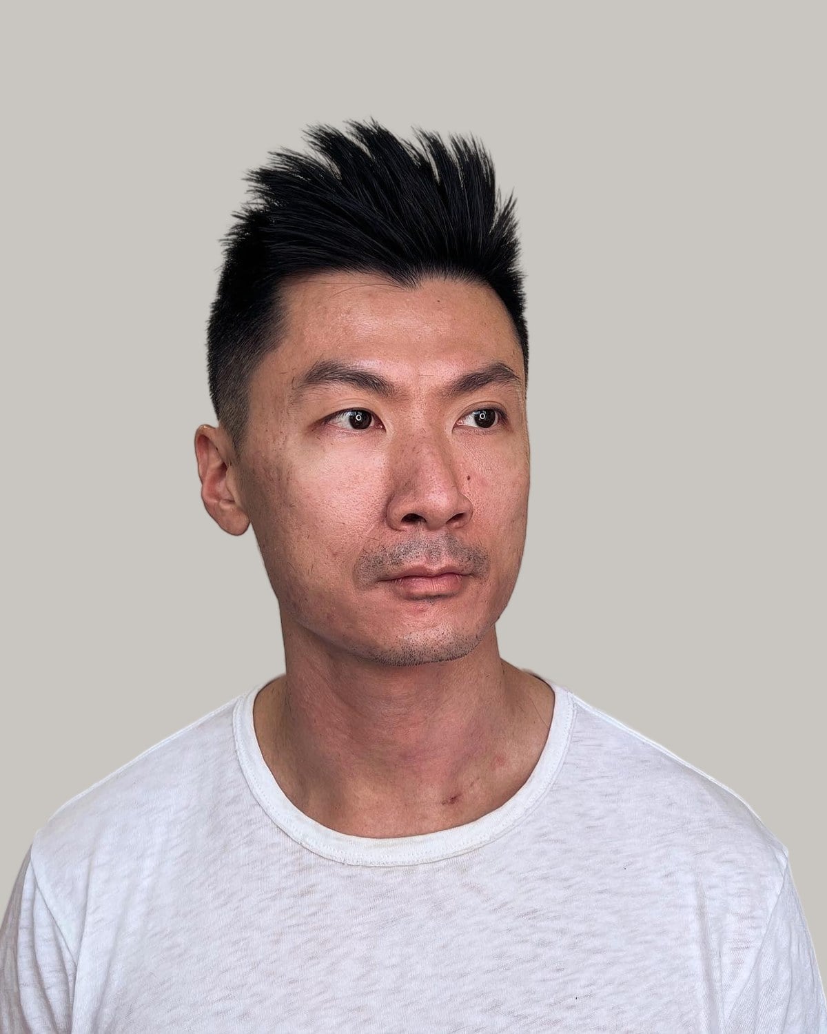 Man with a spiky crew cut on straight black hair, seen from the front