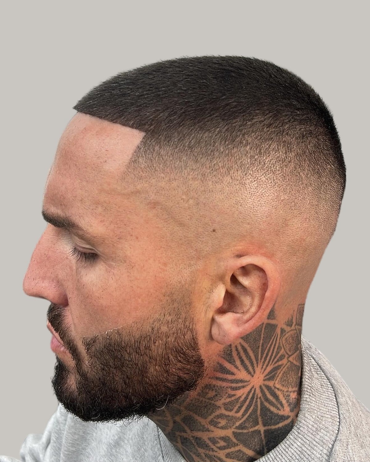 Bearded man with a very short butch cut and a sharp temple line, seen in profile