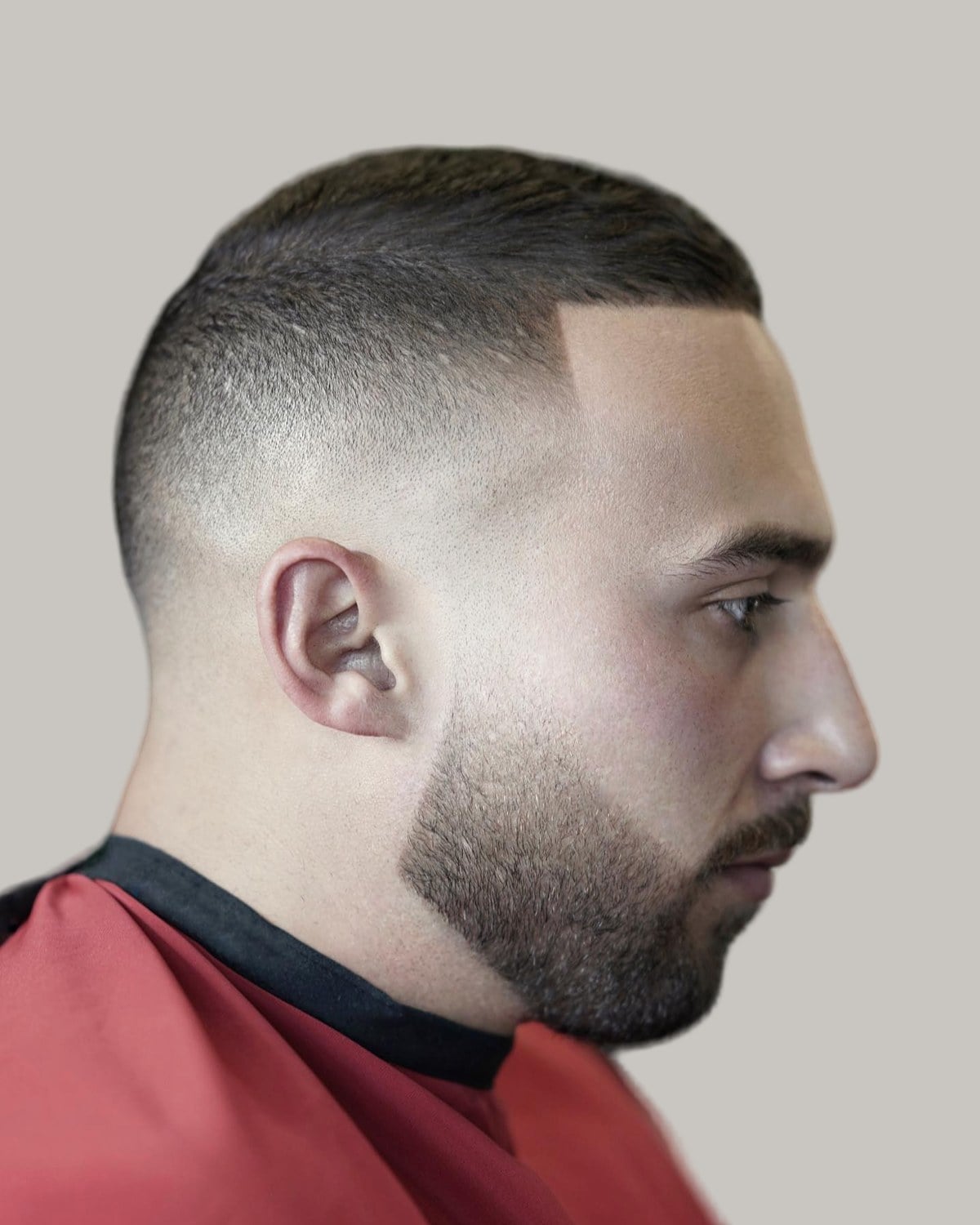 Bearded man with a short crew cut and a high fade, seen in profile