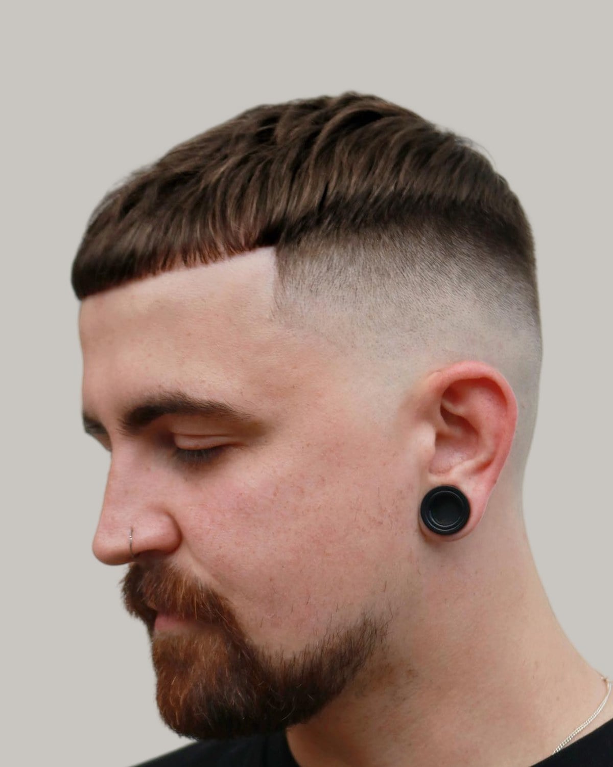 Bearded man with a crew cut and a hard part, seen at an angle