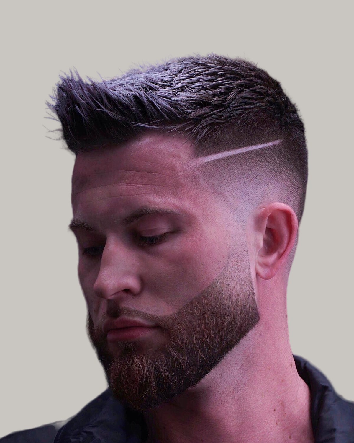 Bearded man with a textured crew cut, a hard part and a high fade, seen at an angle