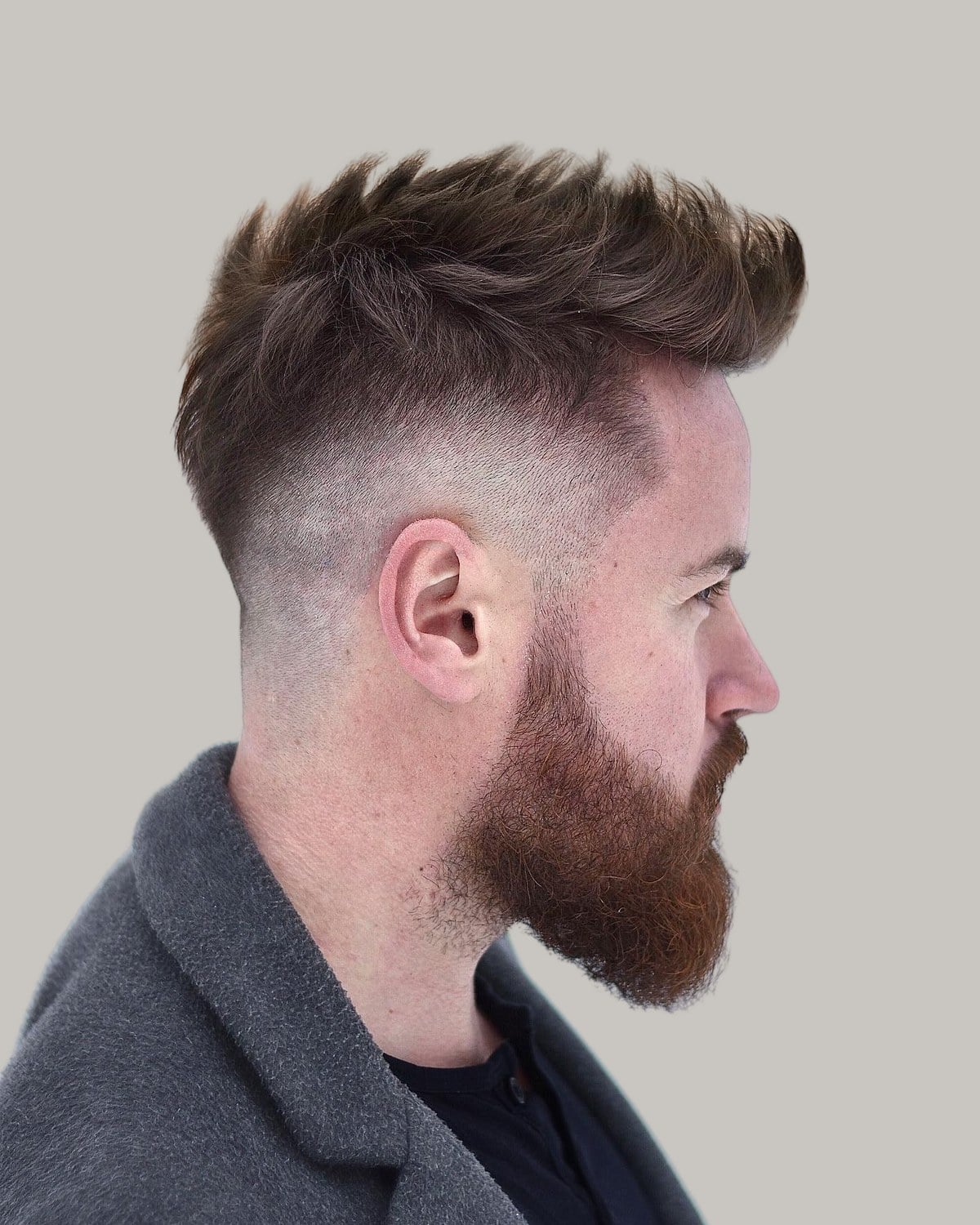 Bearded man with a long crew cut brushed up, seen in profile