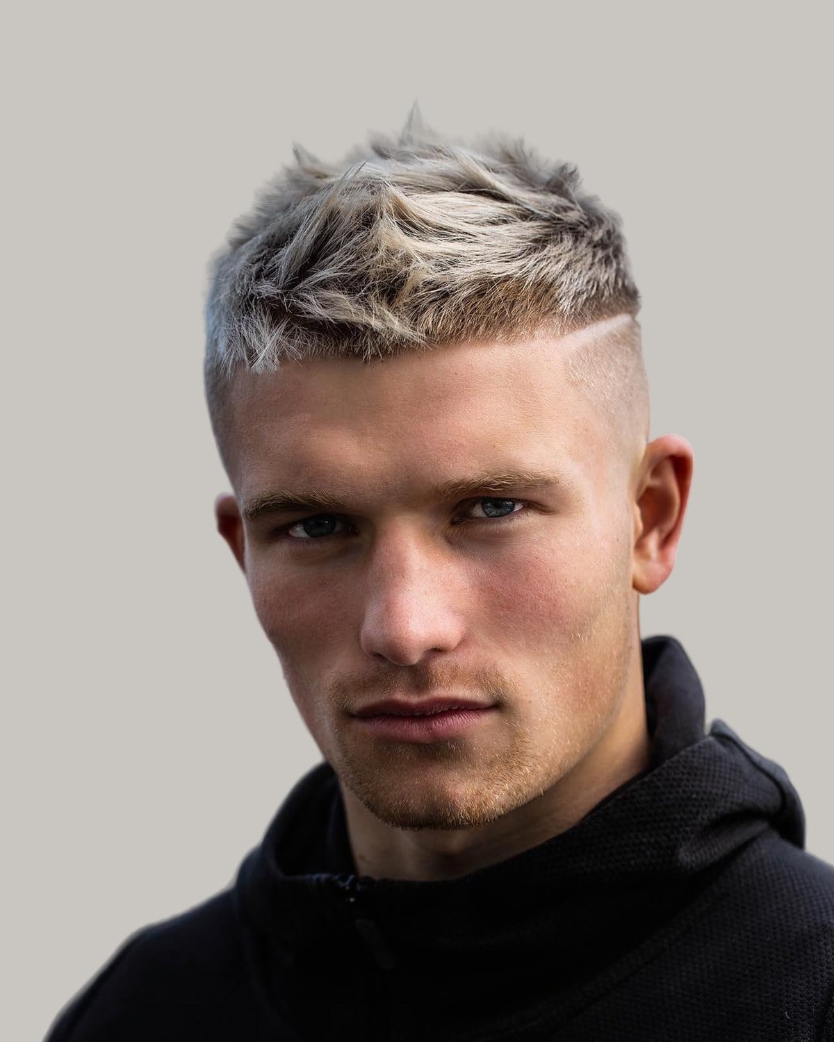 Man with a messy bleached crew cut and a hard part, seen from the front