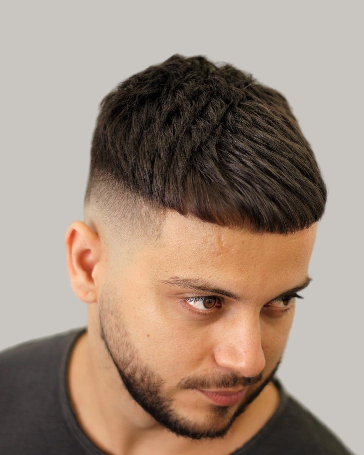 Bearded man with a textured crew cut and a mid fade, seen at an angle