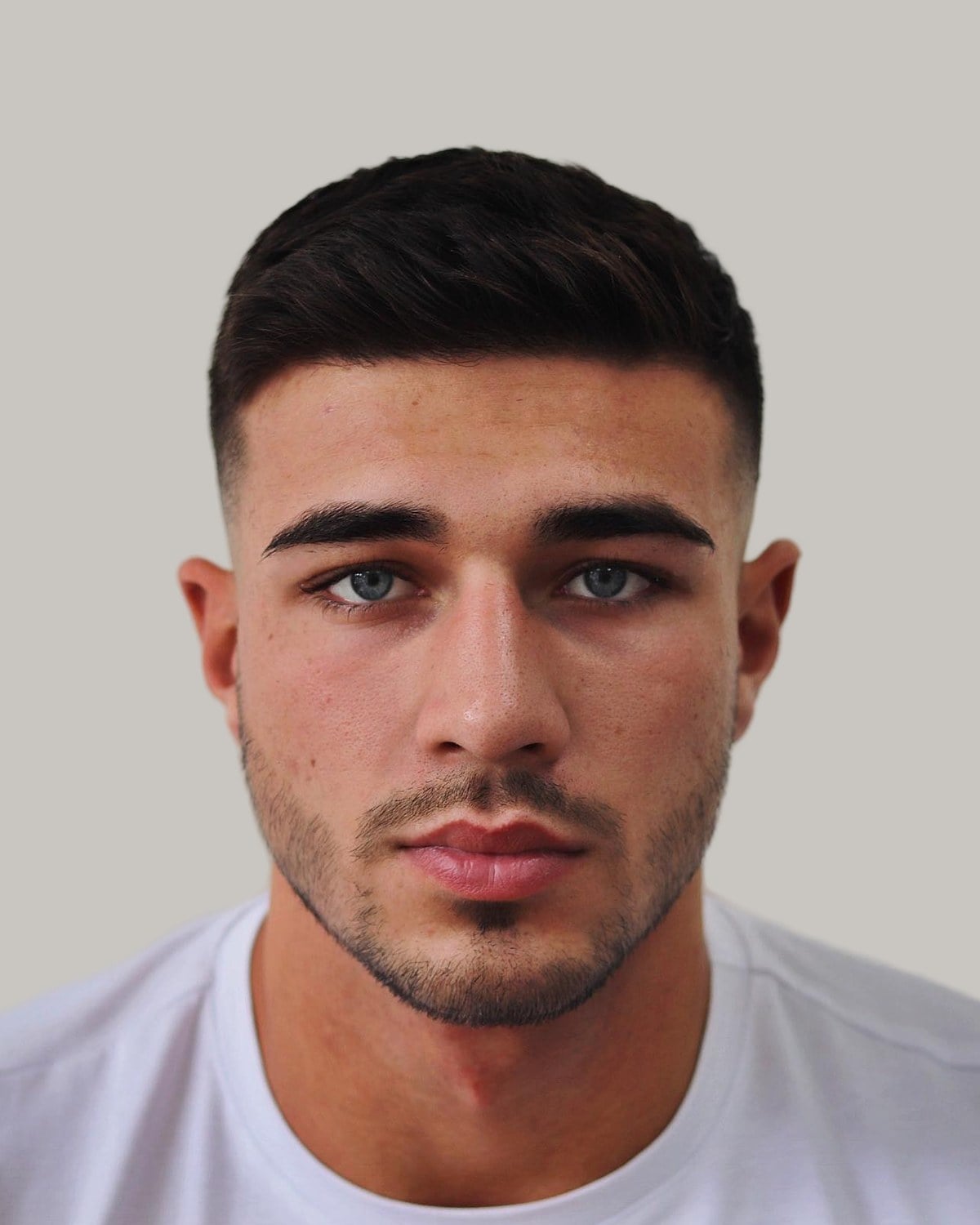 Man with a crew cut and a mid fade, seen from the front