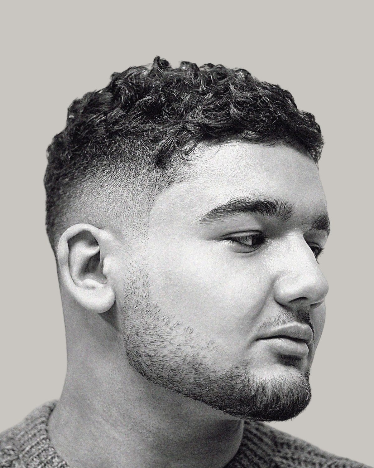 Man with a short curly textured crew cut, seen at an angle in black and white