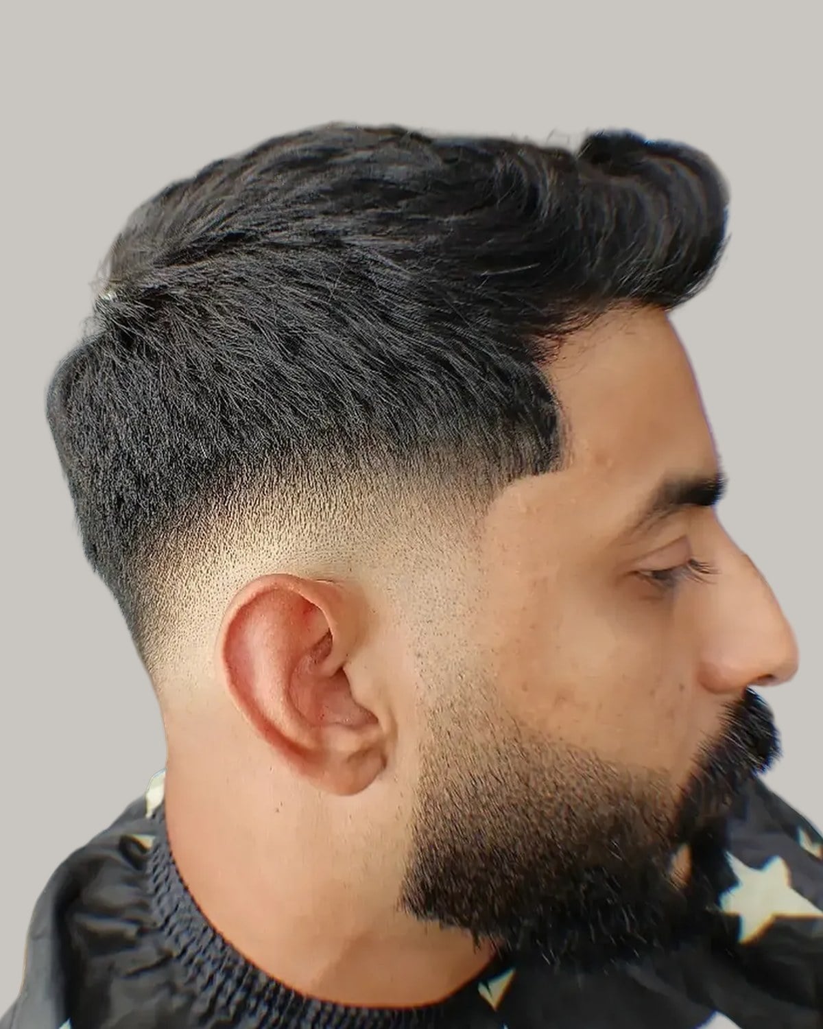 Bearded man with a textured crew cut and a skin fade, seen in profile