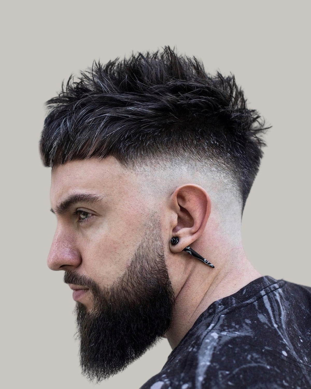 Bearded man with a spiky crew cut and a skin fade, seen in profile