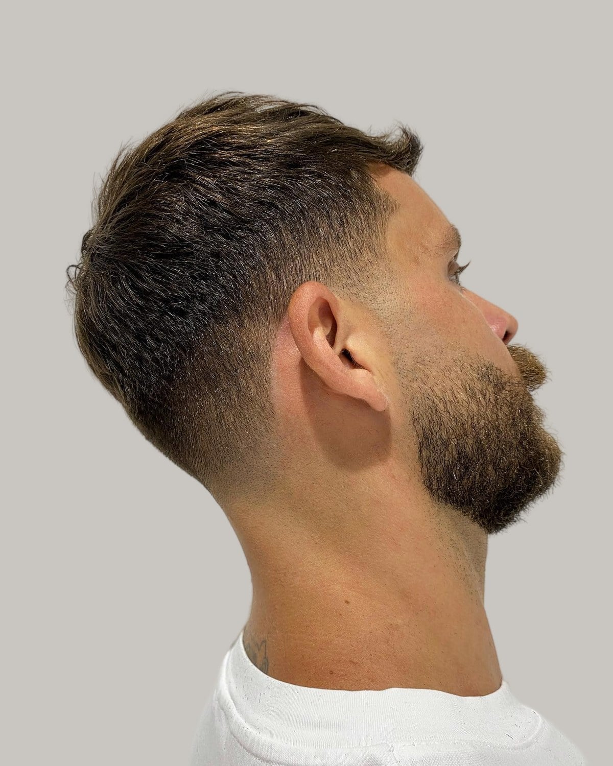 Bearded man with a crew cut and a taper fade, seen in profile