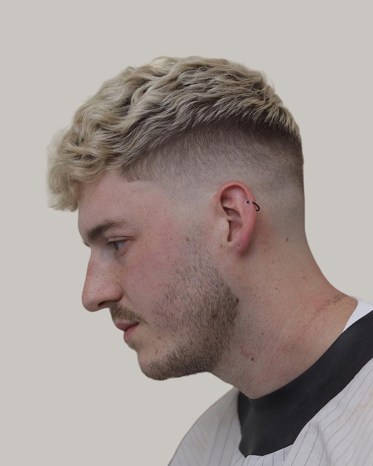 Man with a bleached blond textured crew cut, seen in profile