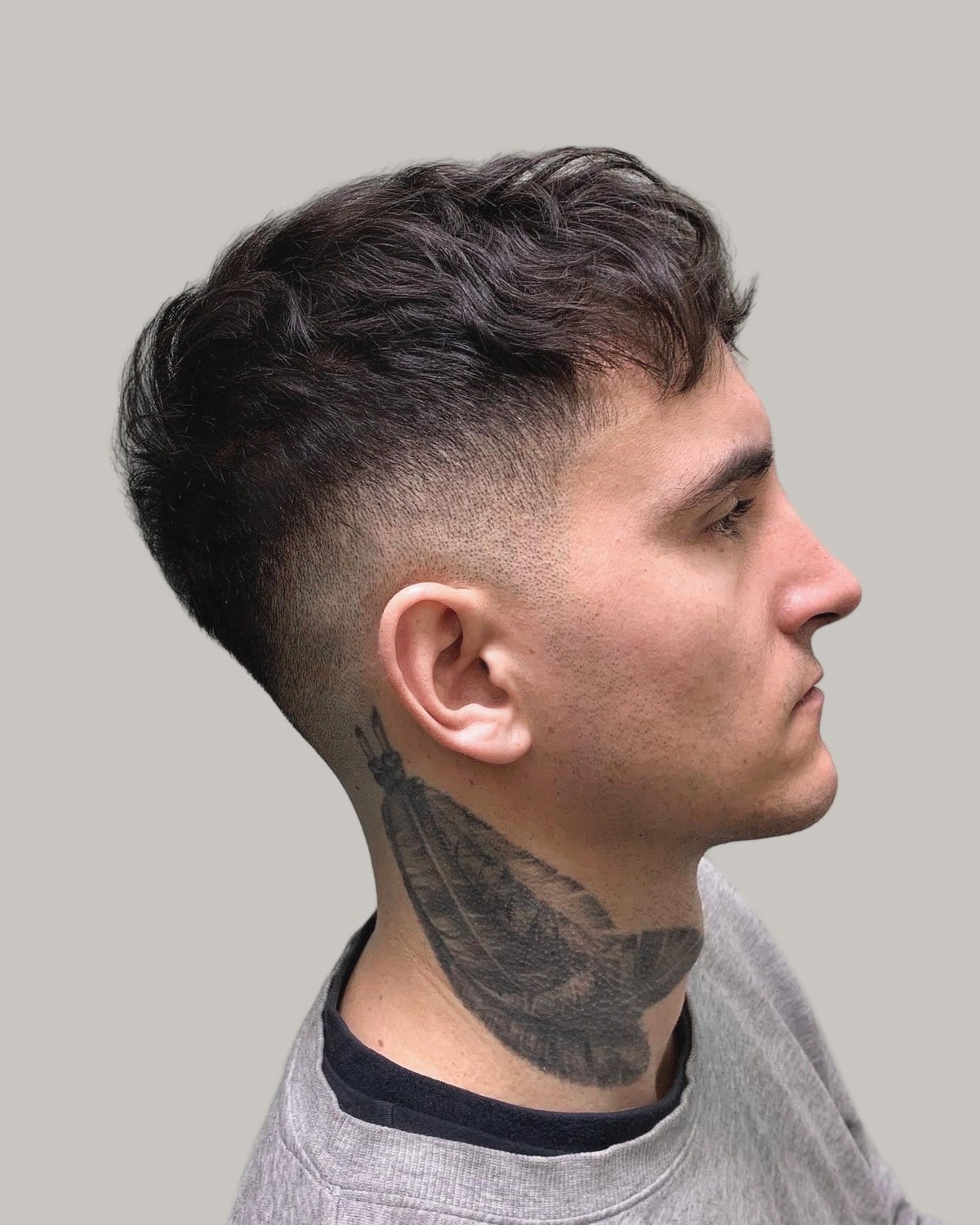 Man with a textured crew cut and a low fade, seen in profile