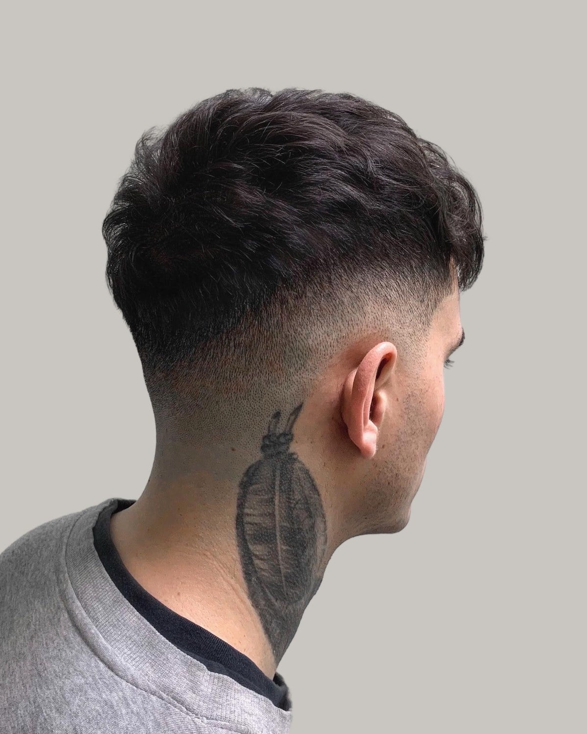 Man with a textured crew cut and a low fade, seen from behind at an angle