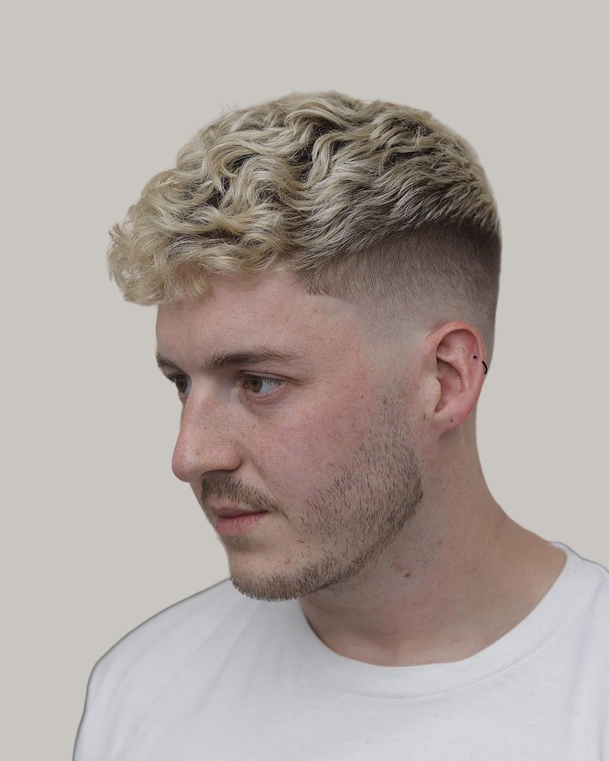 Man with a bleached blond textured crew cut, seen at an angle