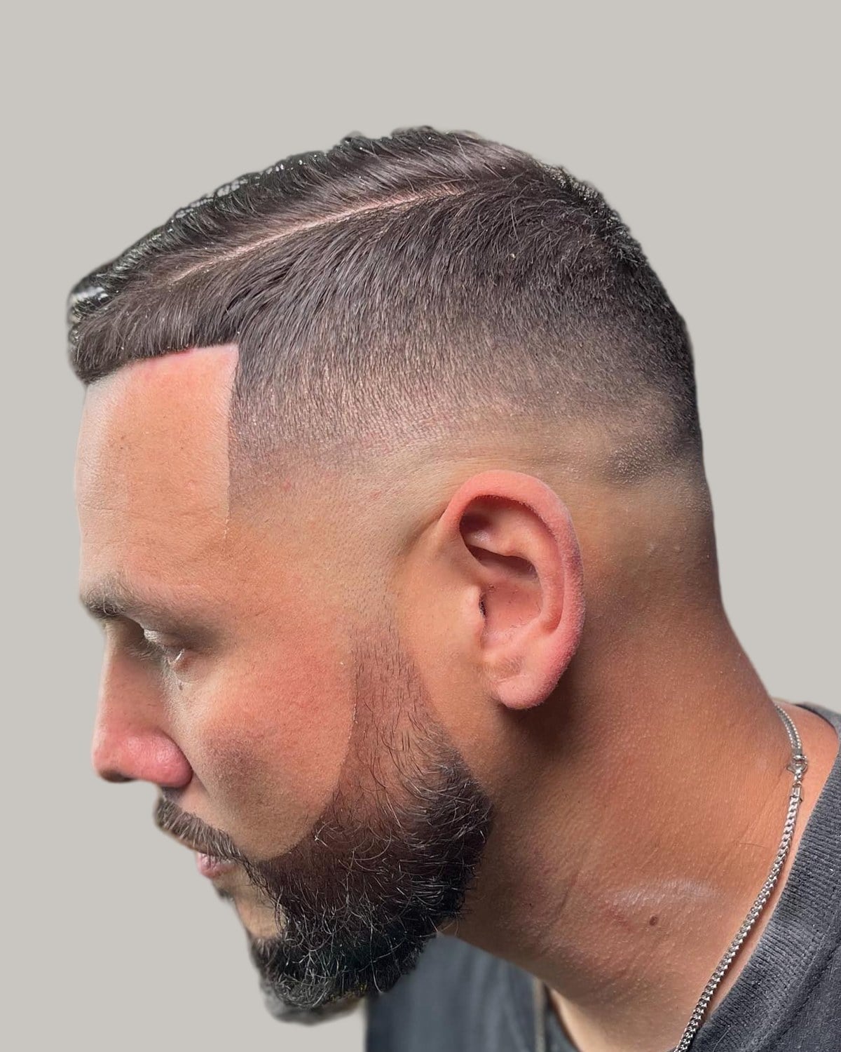 Bearded man with a crew cut and a hard part, seen in profile