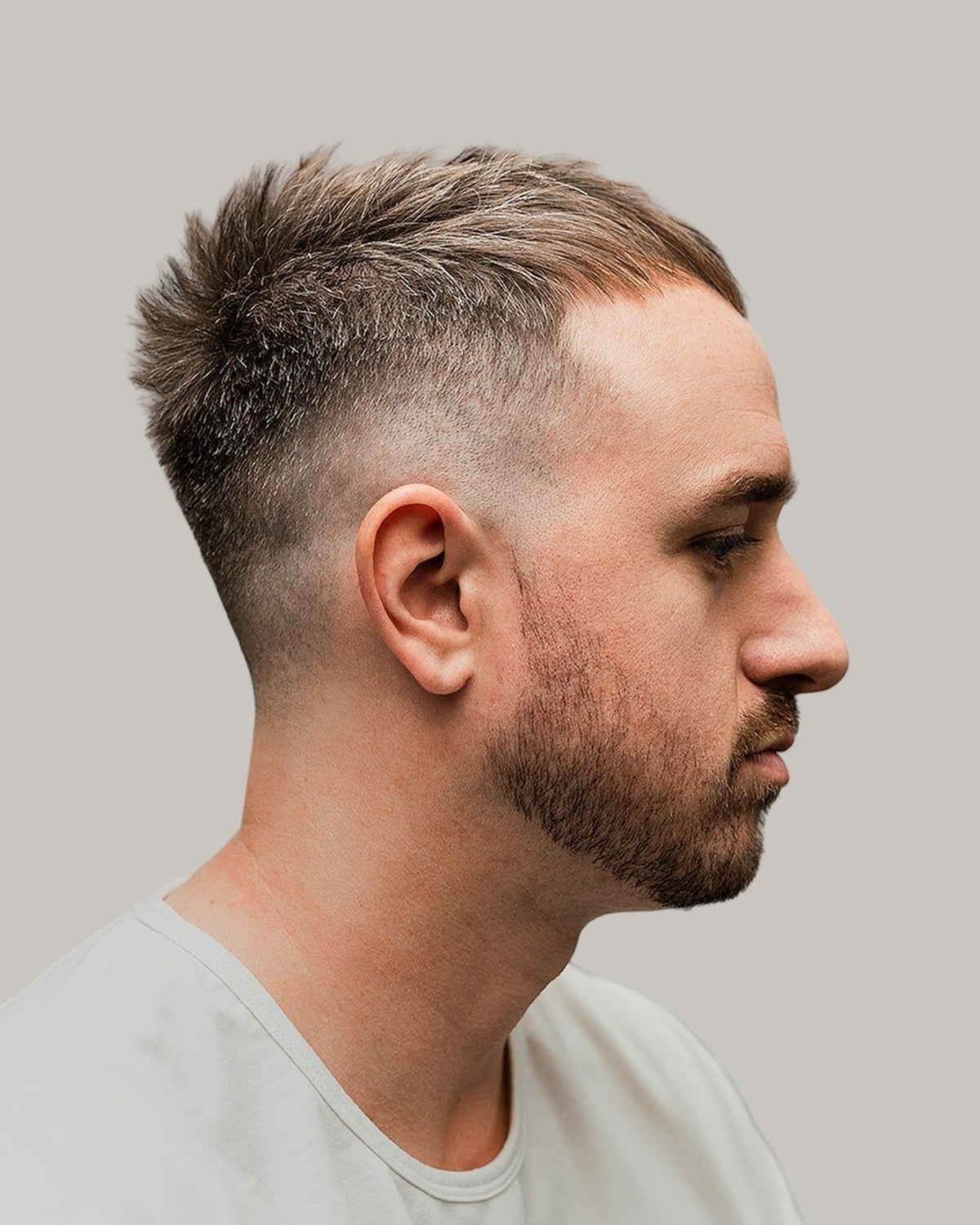 Man with a short textured crew cut and thinner hair at the front, seen in profile