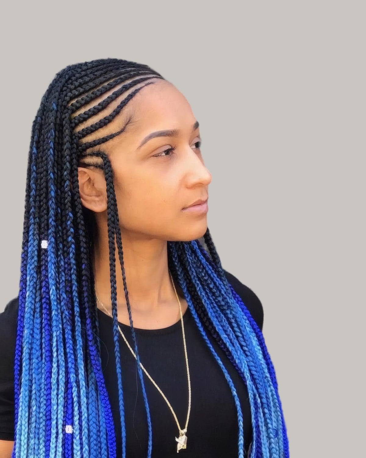 Woman in a black top with Fulani rows and long braids fading from black to bright blue