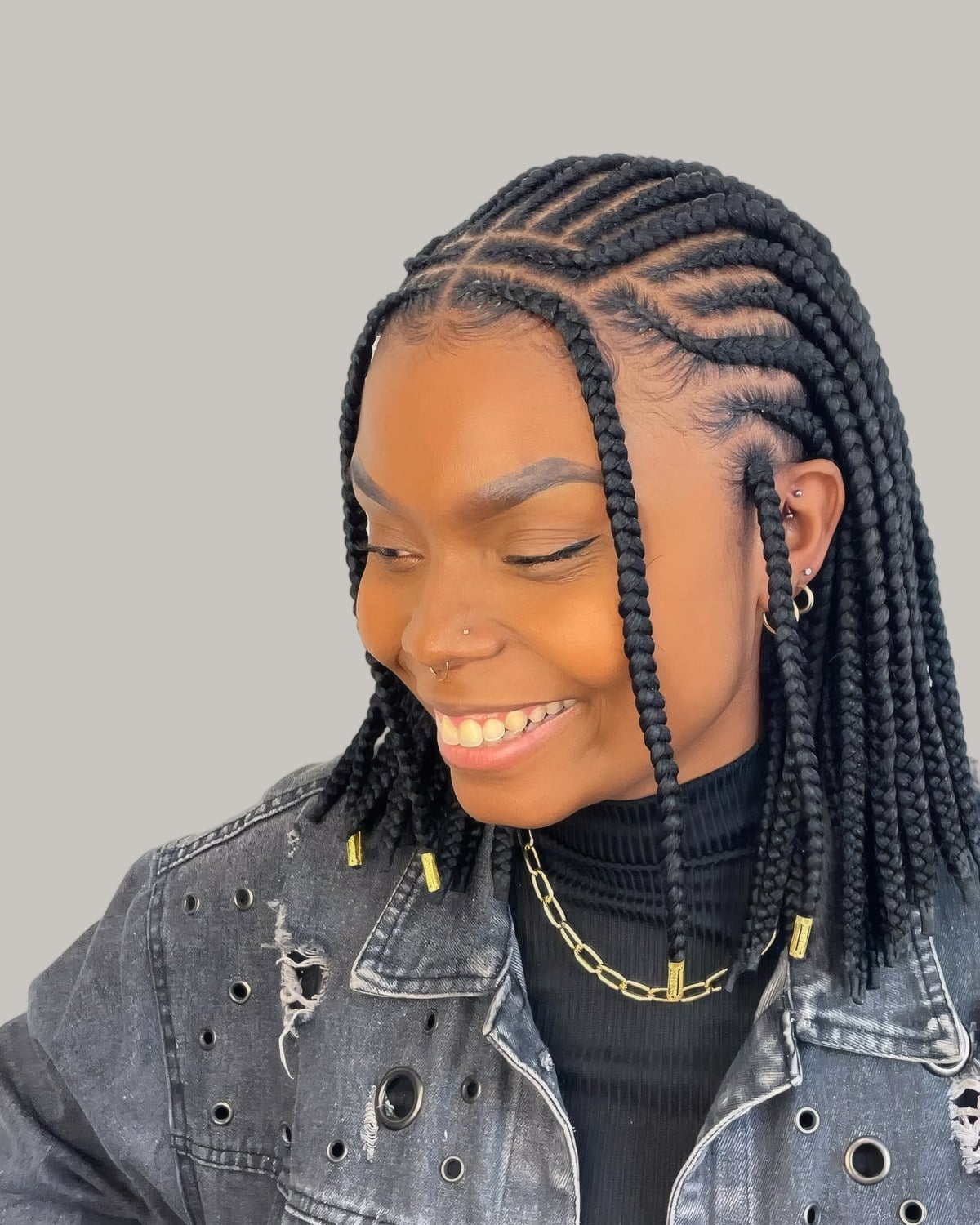 Smiling woman in a denim jacket with a chin-length black Fulani braid bob