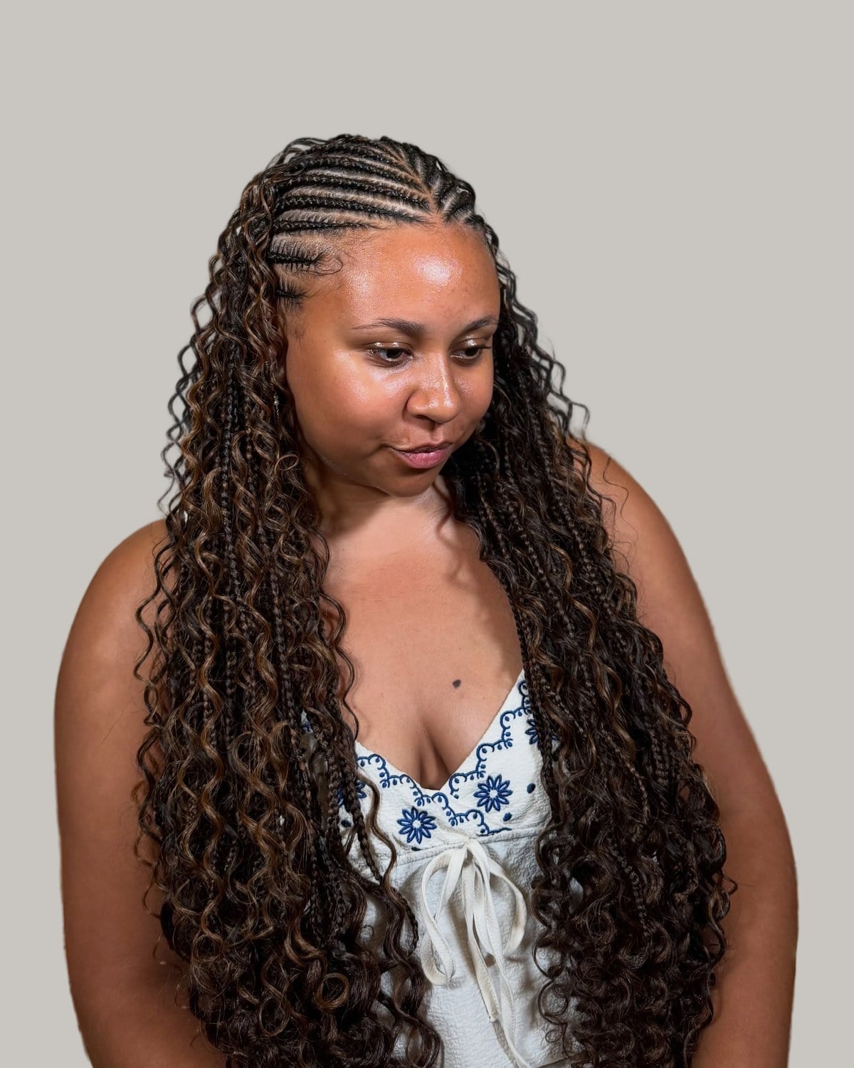 Woman in a white floral top with dark brown boho Fulani braids and curved rows