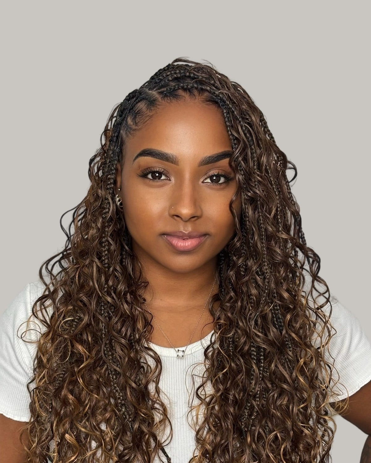 Woman in a white top with boho Fulani braids in brown with honey highlights