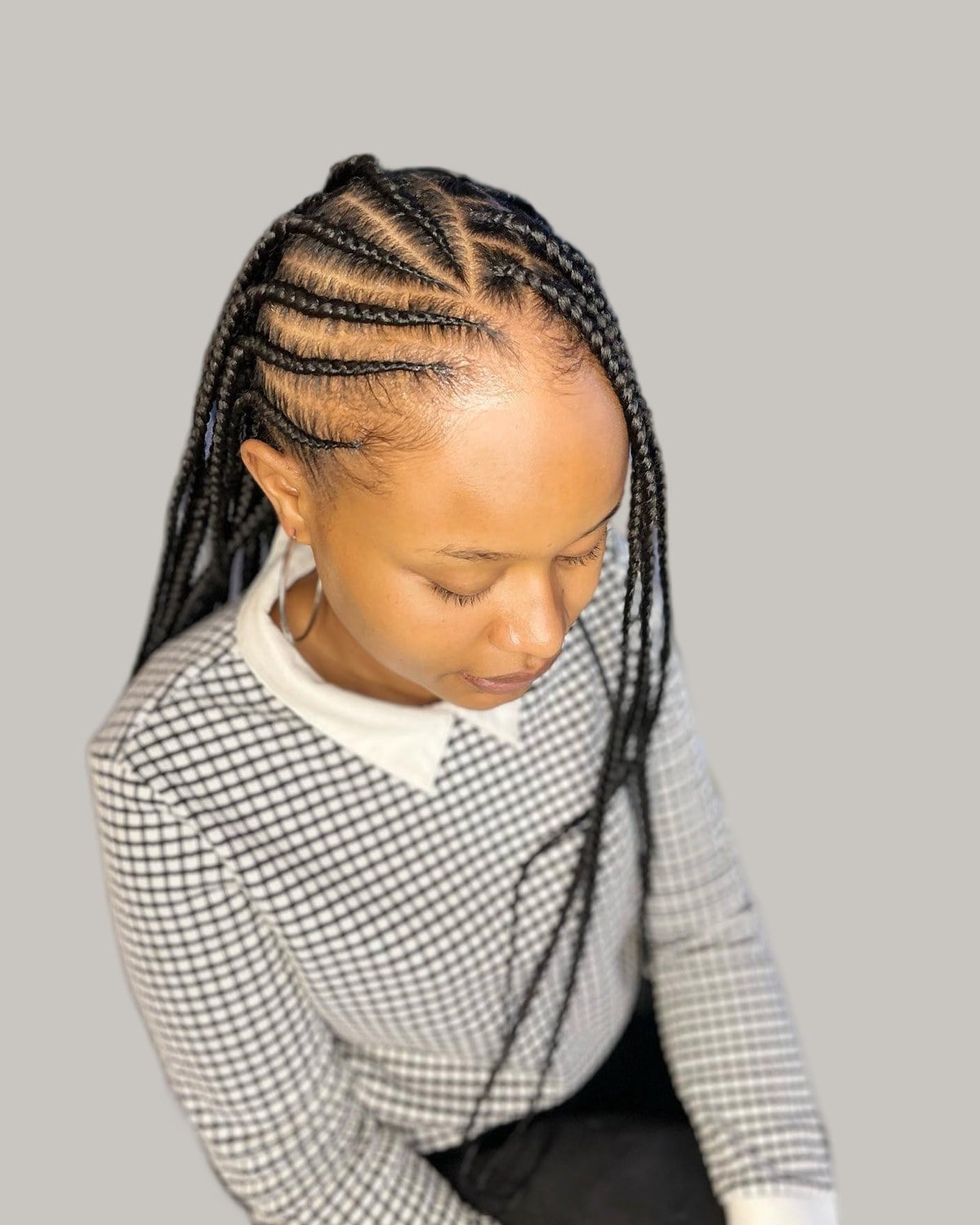 Woman in a gingham top in three-quarter view with Fulani cornrows and long box braids