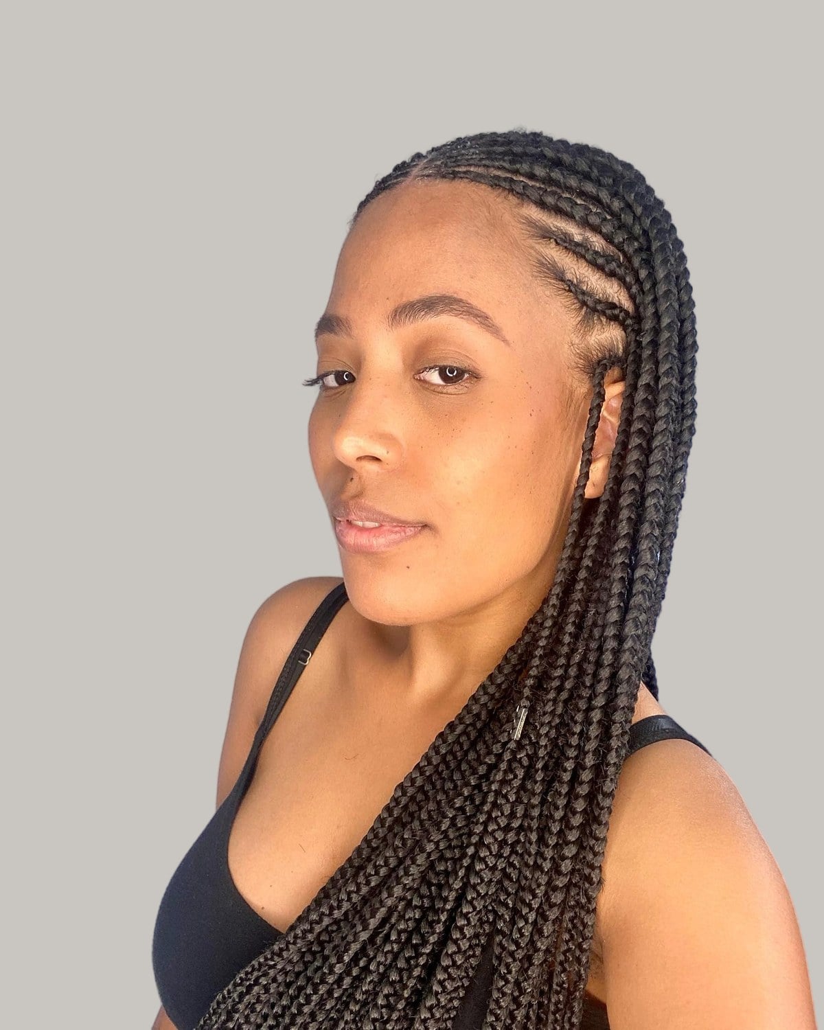 Woman in a black tank top in three-quarter view with long black Fulani braids