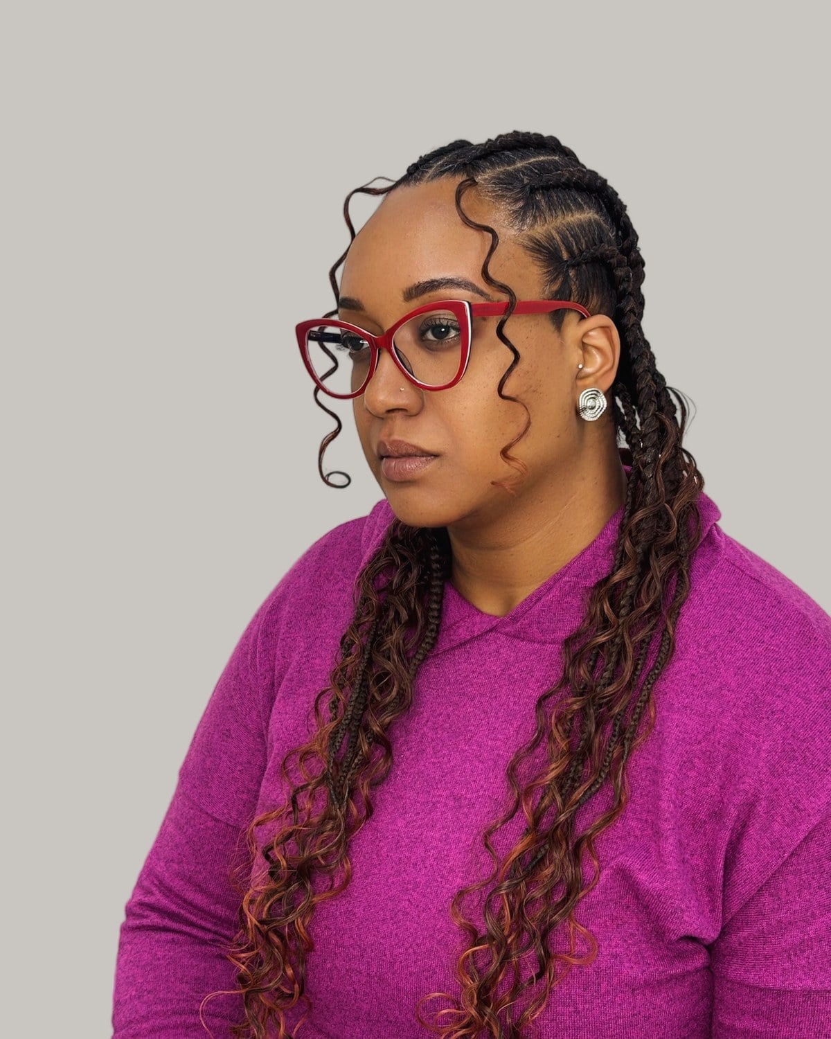 Woman in red glasses looking to one side, Fulani rows and braids with copper curls