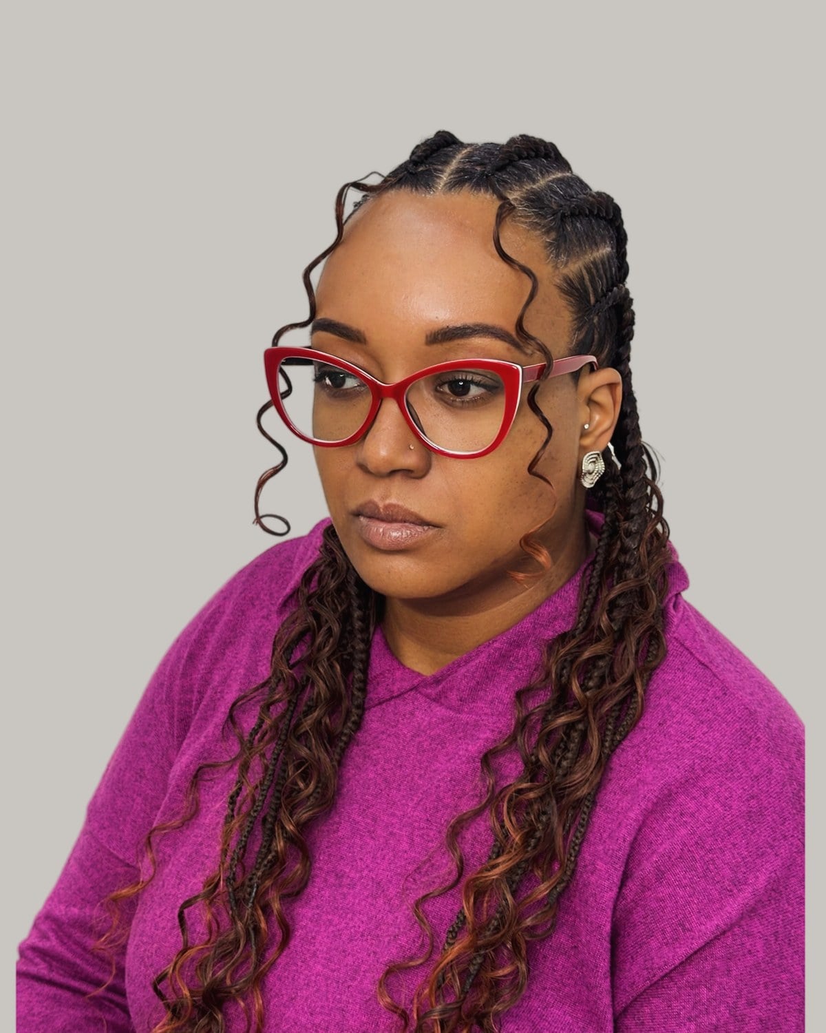 Woman in red glasses and a magenta sweater with Fulani braids and copper curls